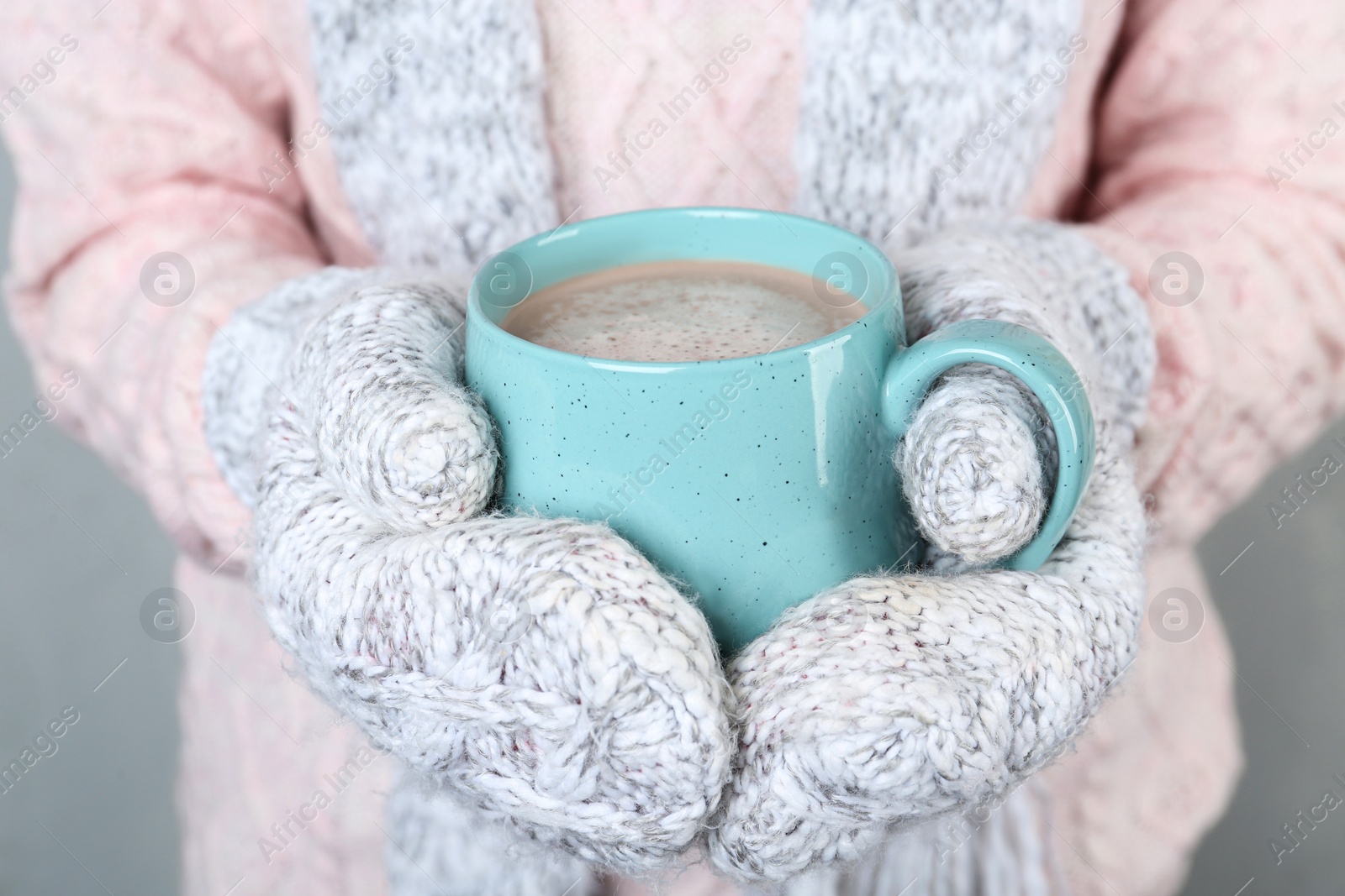 Photo of Woman with knitted mittens holding cup of delicious cocoa drink, closeup