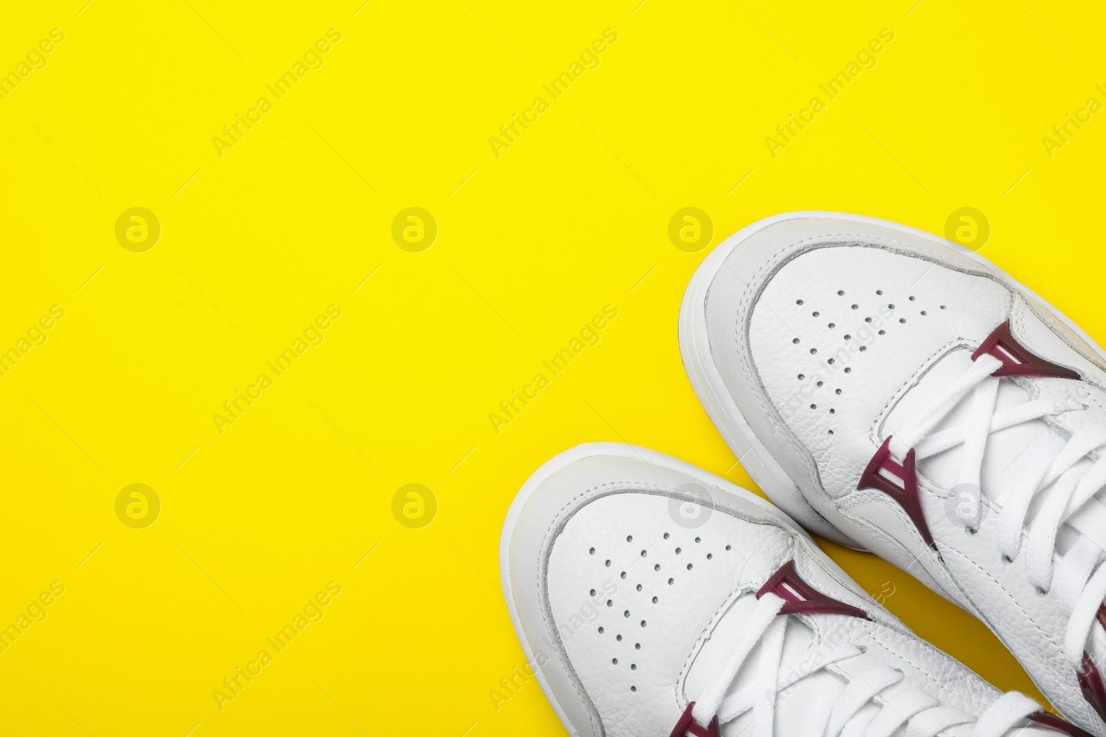 Photo of Pair of stylish shoes on yellow background, top view. Space for text