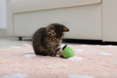Photo of Little kitten playing with toy ball at home
