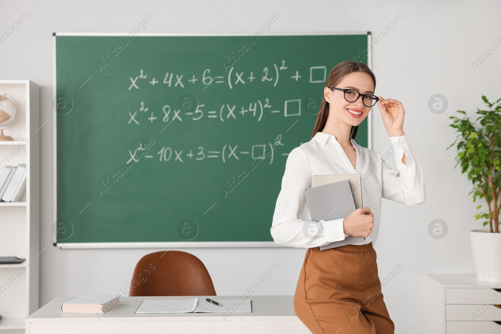 Photo of Portrait of young math’s teacher near chalkboard in classroom