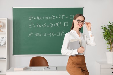 Portrait of young math’s teacher near chalkboard in classroom