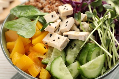 Photo of Delicious vegan bowl with bell pepper, tofu and cucumbers on table, closeup