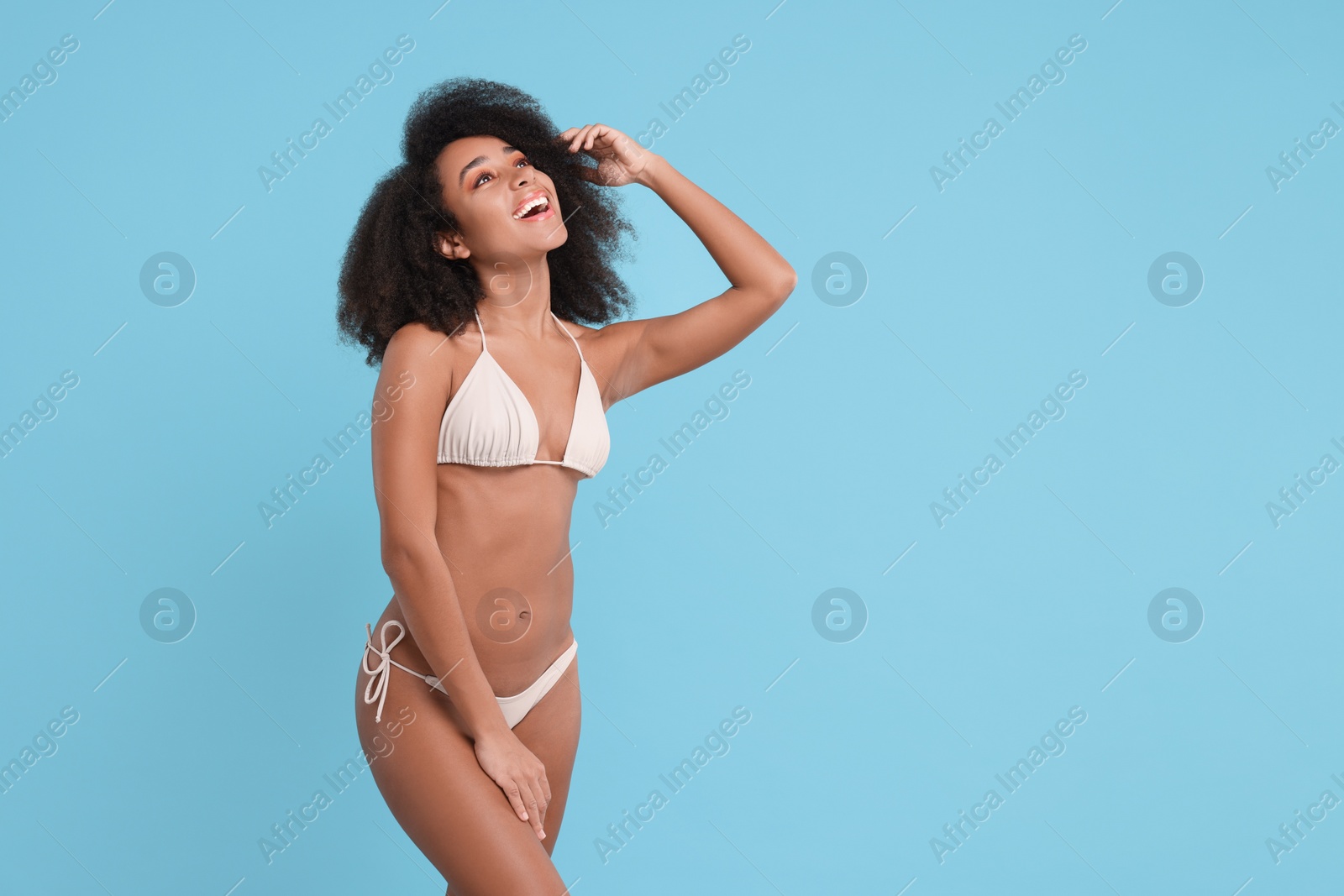 Photo of Beautiful woman in stylish bikini on light blue background, space for text