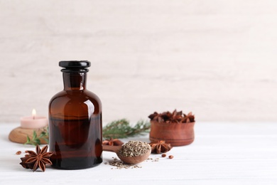 Anise essential oil and spice on white table, space for text