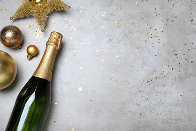 Photo of Happy New Year! Flat lay composition with bottle of sparkling wine on light grey table, space for text