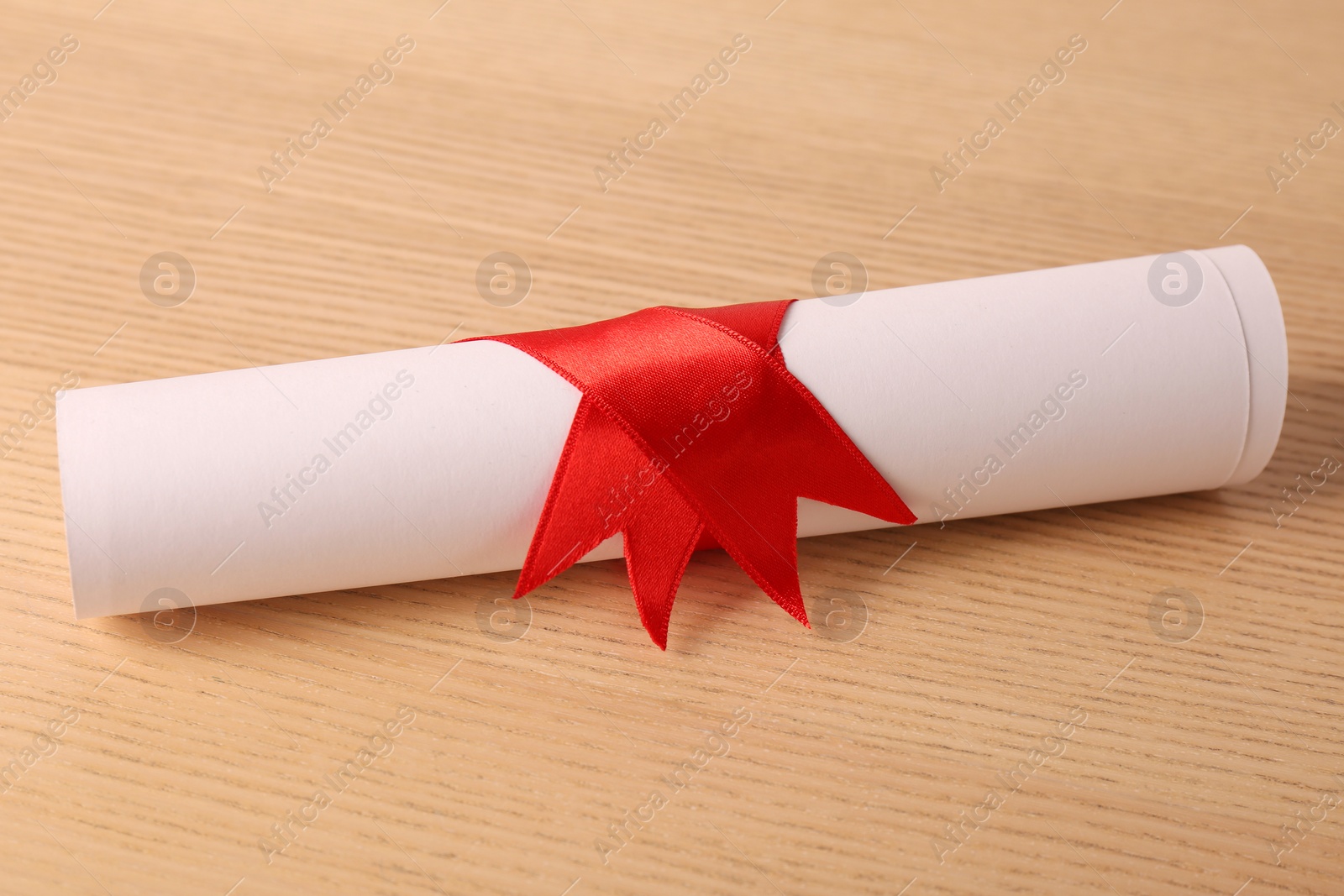 Photo of Graduation diploma tied with ribbon on wooden table