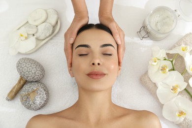 Photo of Young woman receiving facial massage in spa salon, top view