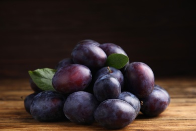 Pile of delicious ripe plums on wooden table