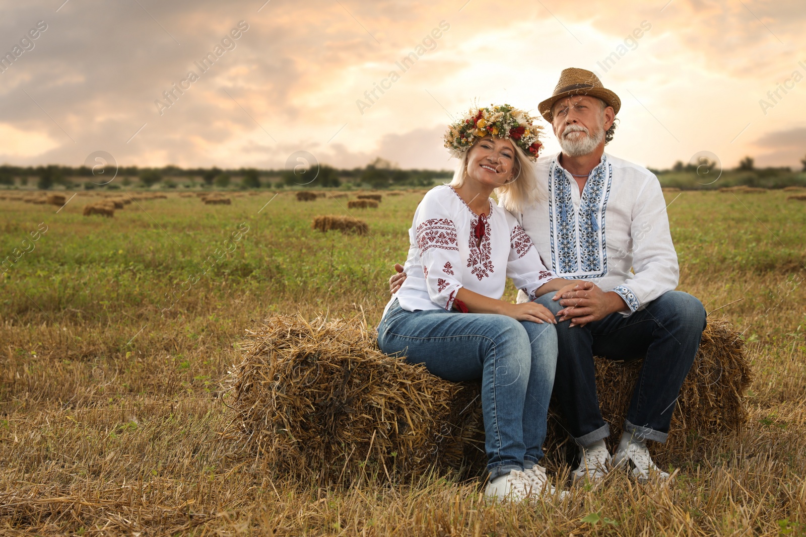 Photo of Happy mature couple wearing Ukrainian national clothes on hay bale in field