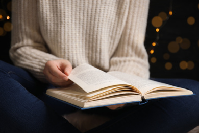 Photo of Young woman reading book at home, closeup