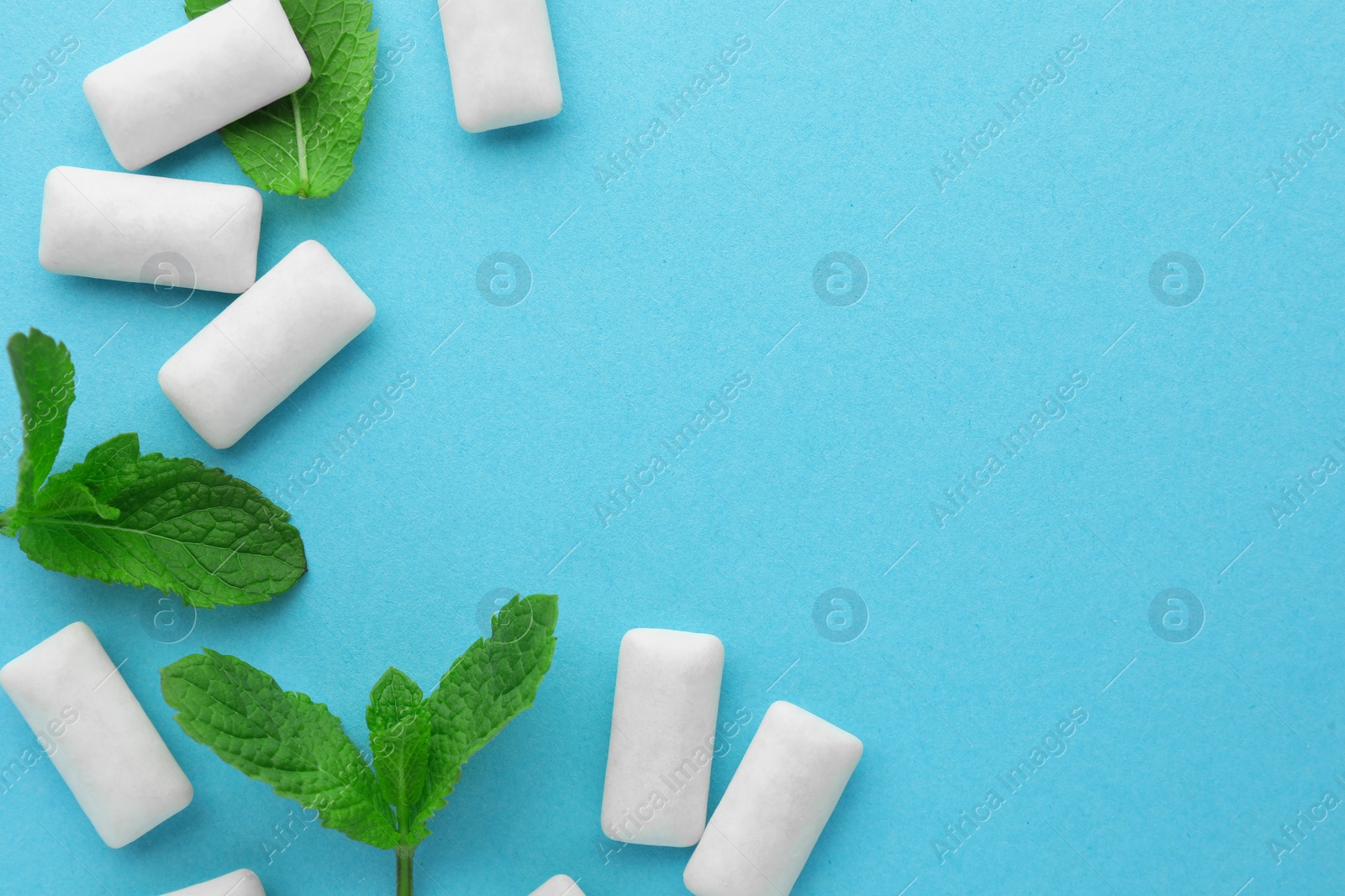 Photo of Tasty white chewing gums and mint leaves on light green background, flat lay. Space for text