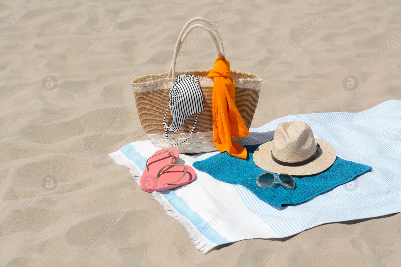 Photo of Blue blanket with towel, bag and beach accessories on sand