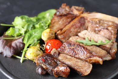 Photo of Delicious grilled beef meat, vegetables and greens on board, closeup