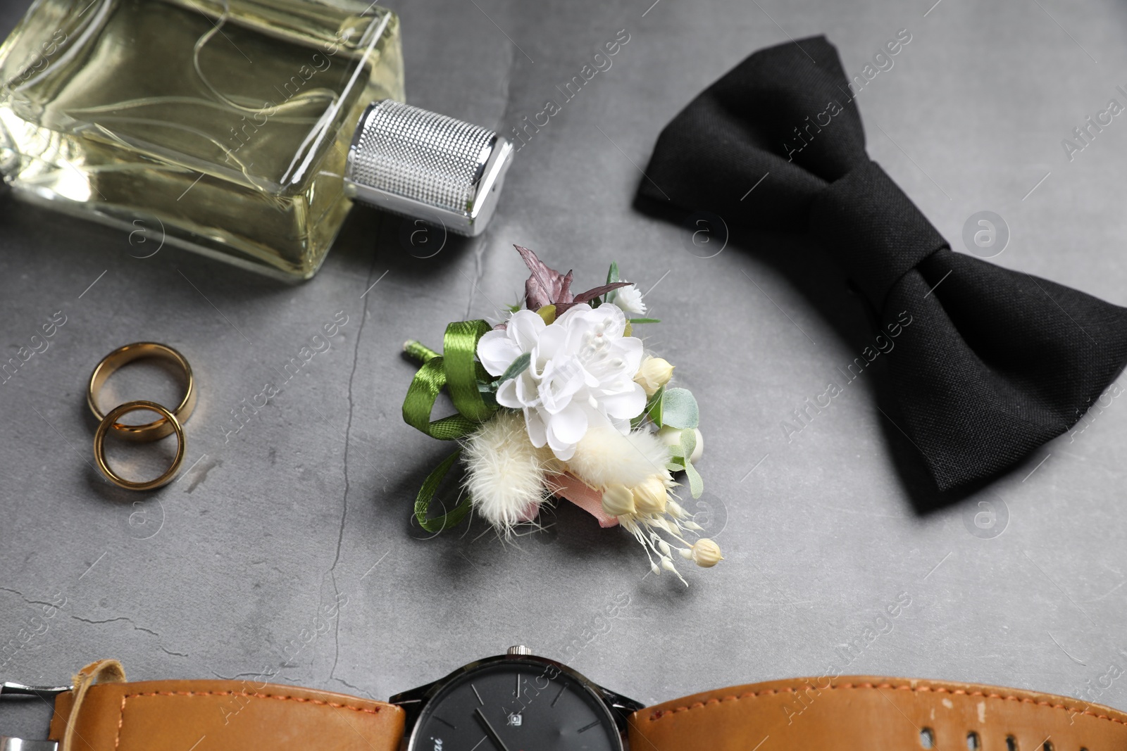 Photo of Wedding stuff. Composition with stylish boutonniere on gray background