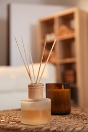 Aromatic reed air freshener and candle on wicker tray in room