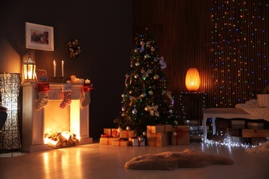 Photo of Stylish living room interior with decorated Christmas tree at night