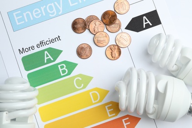 Photo of Flat lay composition with energy efficiency rating chart and light bulbs on white background