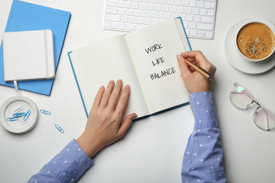 Image of Work-life balance concept. Woman writing in notebook at white table, top view