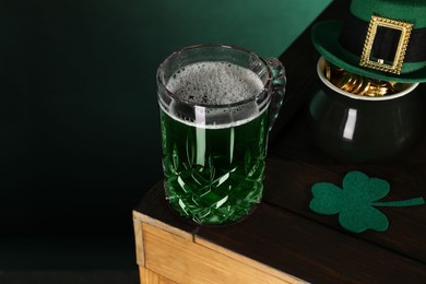 Photo of St. Patrick's day celebration. Green beer, leprechaun hat, pot of gold and decorative clover leaf on wooden table. Space for text