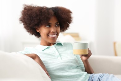 Photo of Smiling African American woman with cup of drink at home