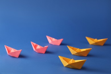 Many pink and orange handmade paper boats on blue background. Origami art