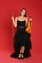 Photo of Beautiful woman with violin on red background