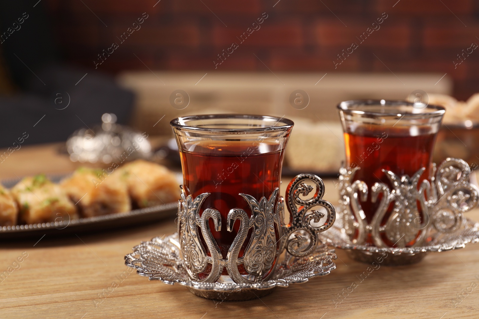 Photo of Glasses of traditional Turkish tea in vintage holders on wooden table