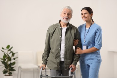 Smiling nurse supporting elderly patient in hospital, space for text