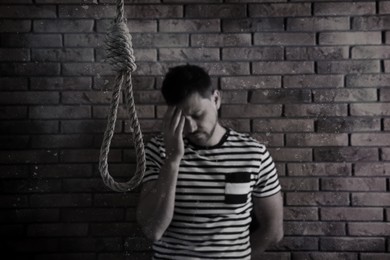 Image of Depressed man near brick wall, focus on rope noose. Suicide concept