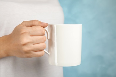 Photo of Woman holding ceramic cup on color background. Mock up for design