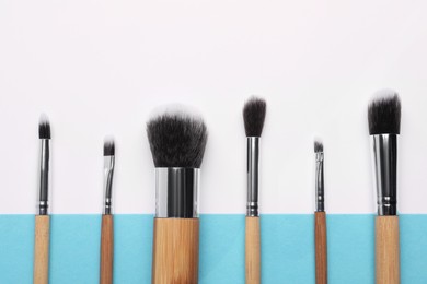Photo of Different makeup brushes on color background, flat lay