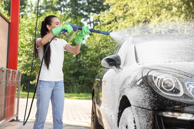 Photo of Woman covering automobile with foam at outdoor car wash