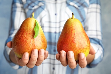 Woman holding ripe juicy pears on blue background, closeup