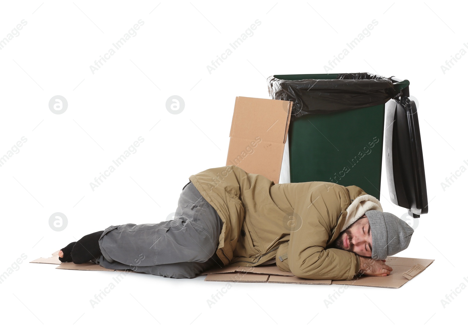 Photo of Poor homeless man lying near trash bin isolated on white