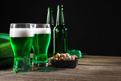 St. Patrick's day party. Green beer, nuts, leprechaun hat and decorative clover leaves on wooden table. Space for text