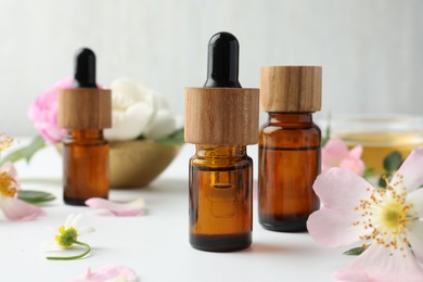 Photo of Aromatherapy. Essential oils and flowers on white table, closeup