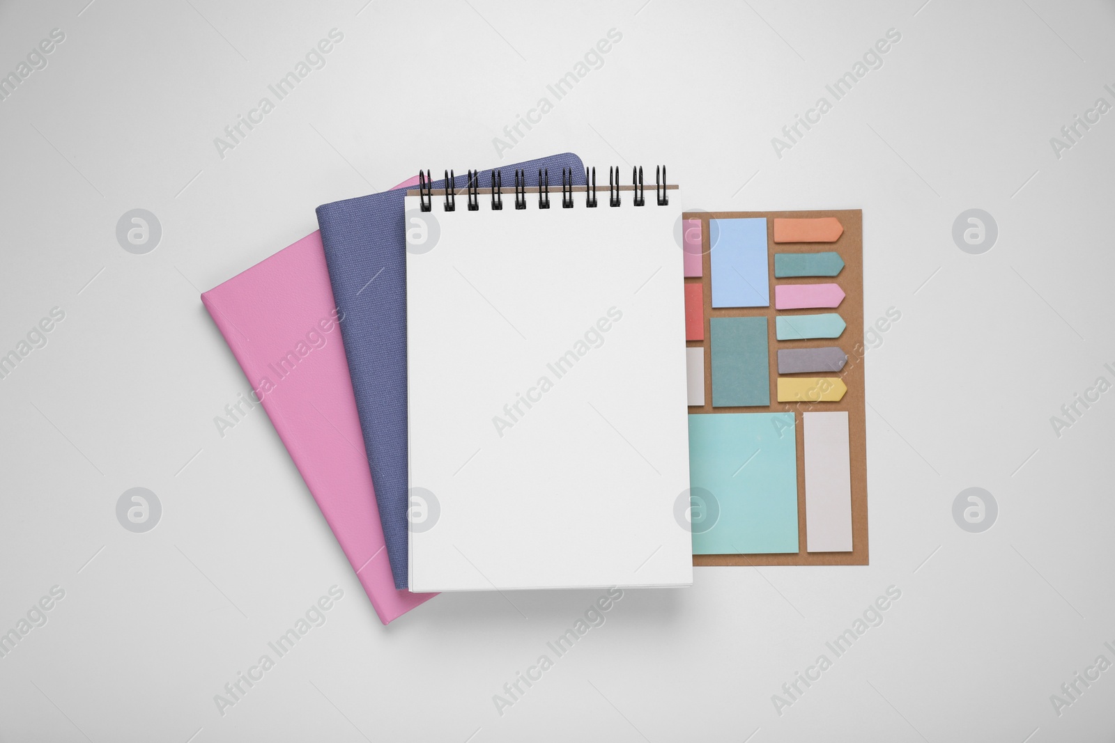 Photo of Monthly planners and stationery on white background, flat lay