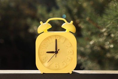 Yellow alarm clock outdoors on sunny morning