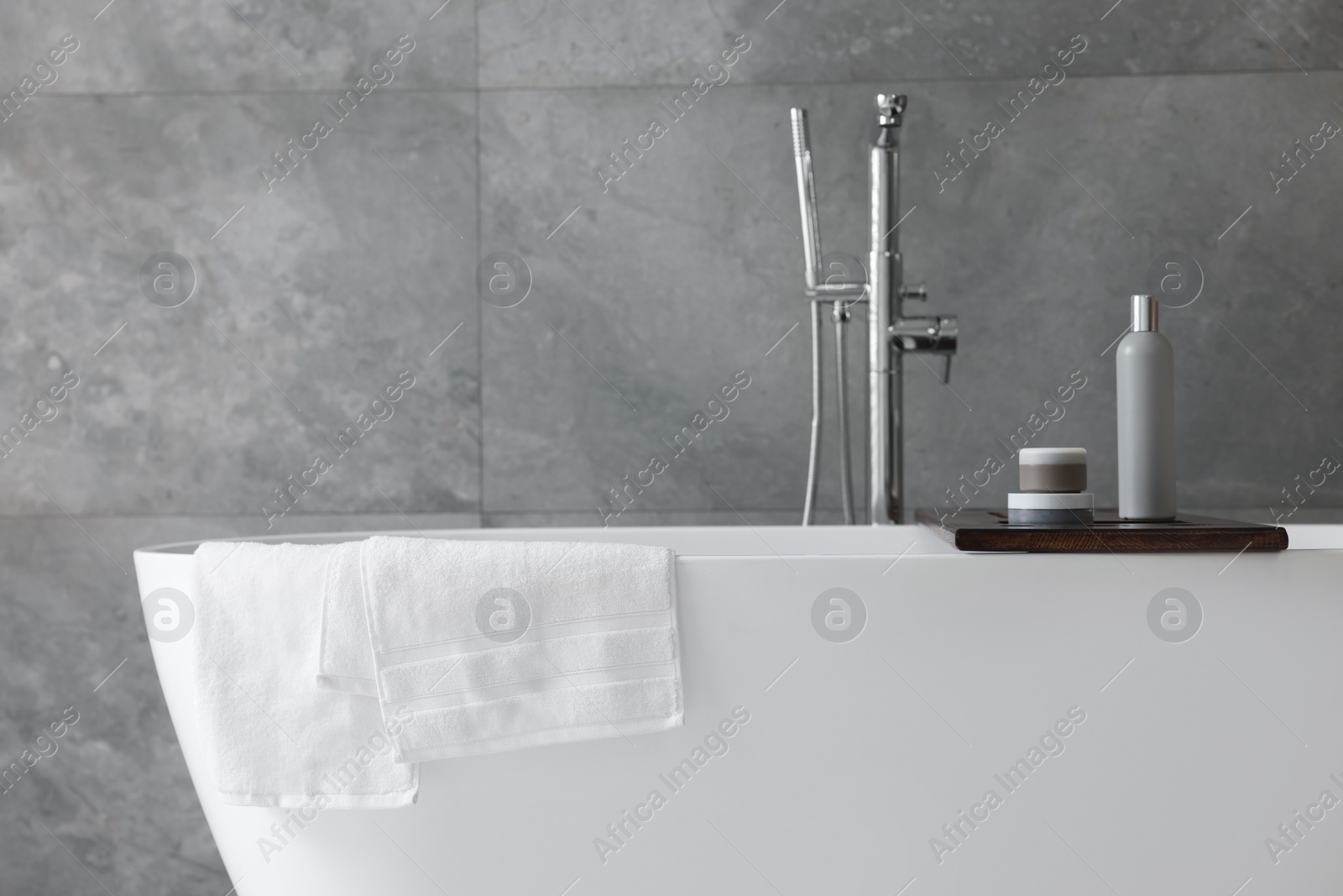 Photo of Fresh white towels on tub in bathroom