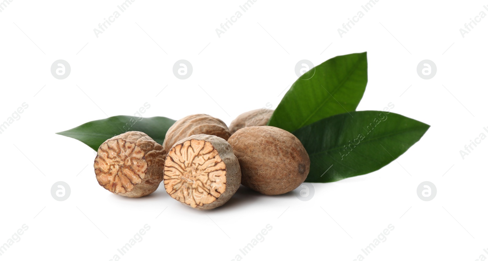 Photo of Nutmeg seeds with green leaves on white background