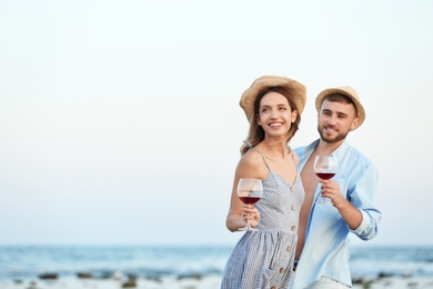 Photo of Young couple with glasses of wine on beach