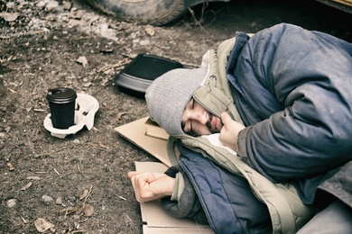 Poor homeless man lying on ground outdoors