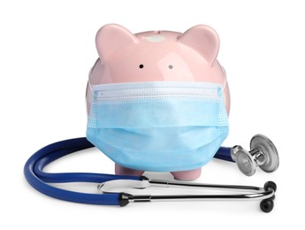 Piggy bank in protective mask and stethoscope on white background. Medical insurance