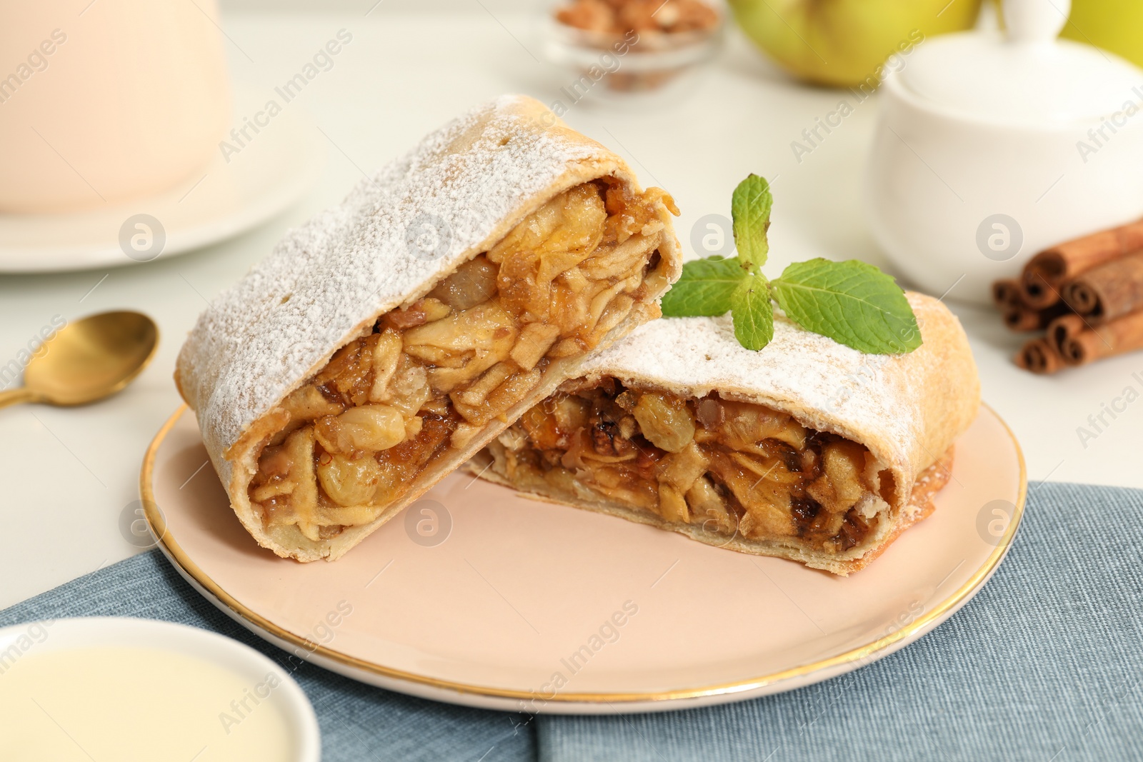 Photo of Delicious strudel with apples, nuts and raisins on table, closeup