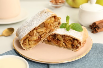 Delicious strudel with apples, nuts and raisins on table, closeup