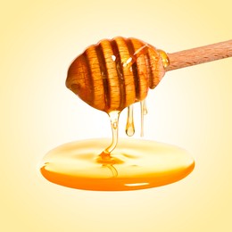 Image of Natural honey dripping from dipper on pale yellow background