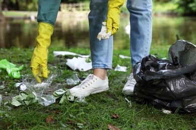 Woman with plastic bag collecting garbage in park, closeup