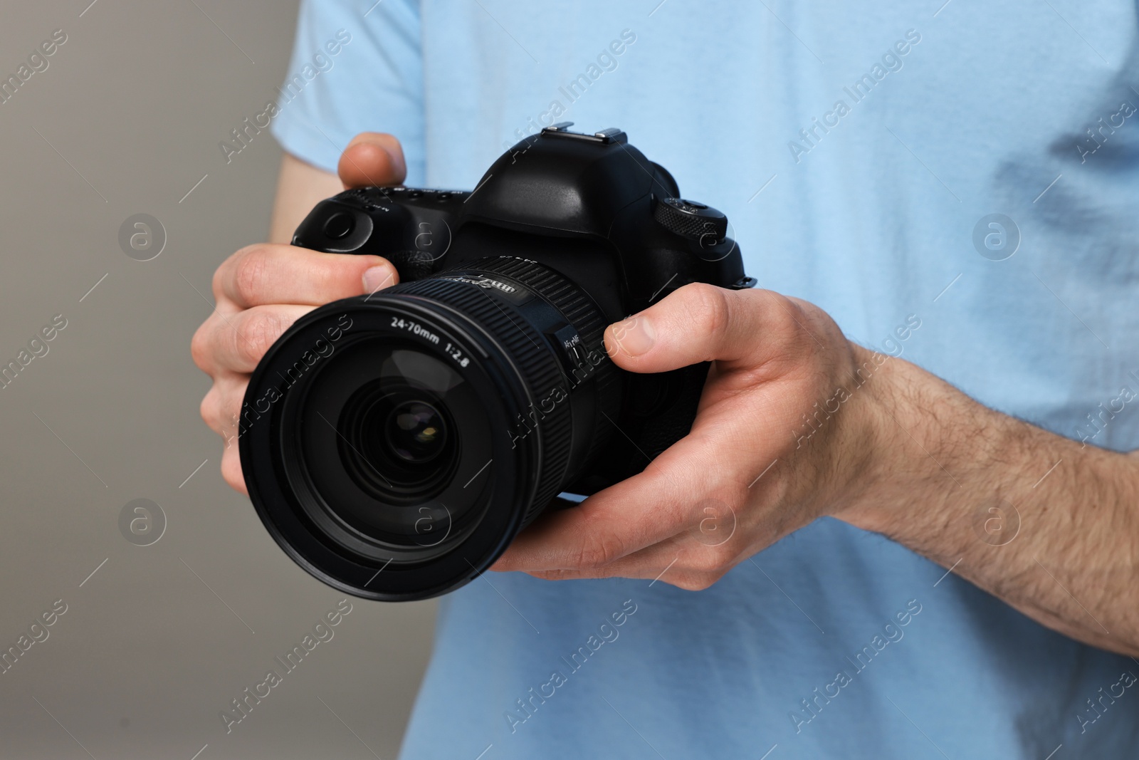 Photo of Photographer holding camera on grey background, closeup