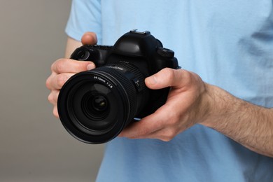 Photo of Photographer holding camera on grey background, closeup