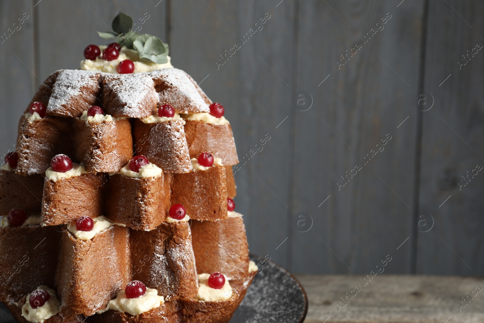 Photo of Delicious Pandoro Christmas tree cake with powdered sugar and berries on wooden table, closeup. Space for text